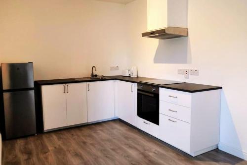 uma cozinha com armários brancos e um frigorífico de aço inoxidável em Secluded Modern Guest House em Castletown Gheoghegan