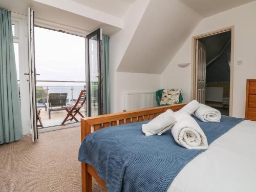 a bedroom with a bed and a view of the ocean at Little Trelawns in Mawgan Porth