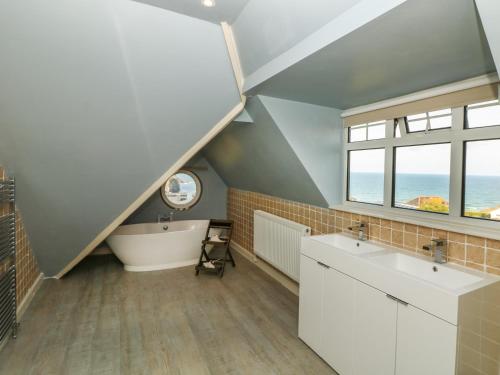 茅根海岸的住宿－Little Trelawns，阁楼浴室配有浴缸、水槽和浴缸。