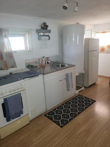 La cuisine est équipée d'une cuisinière, d'un évier et d'un réfrigérateur. dans l'établissement le bungalow au fond du jardin, à Valeilles