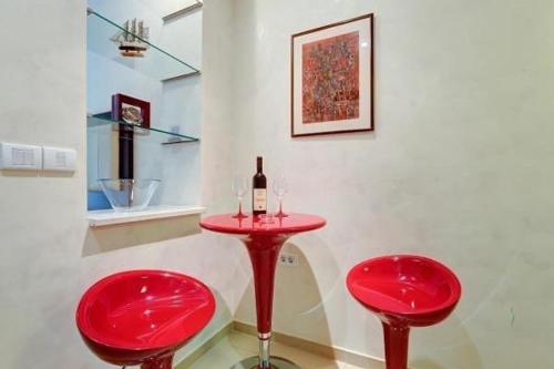 een rode tafel met twee rode stoelen en een fles wijn bij Splendid Luxury Apartments in Budva