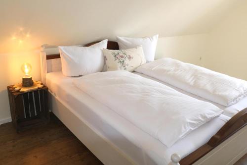 a large white bed with white sheets and pillows at Ferienwohnung Hof Margarethental in Goldelund