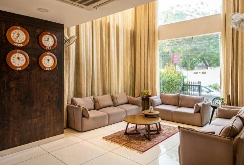 a living room with couches and a table and clocks at M Square Hotel in Hyderabad