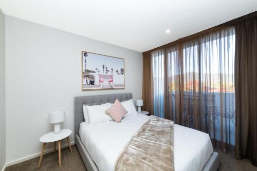 um quarto com uma cama e uma grande janela em Arte Apartments Braddon em Camberra