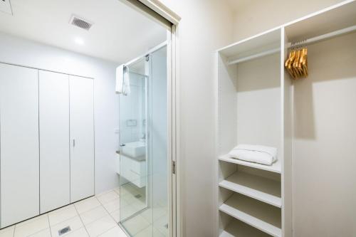 uma casa de banho com paredes brancas e uma cabina de duche em vidro. em Arte Apartments Braddon em Camberra