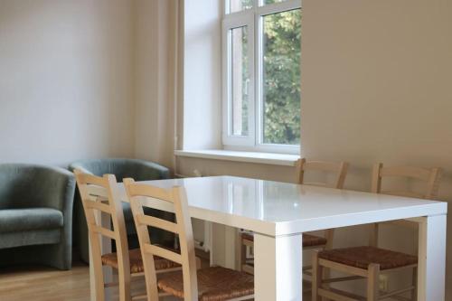 une table à manger blanche avec des chaises et une fenêtre dans l'établissement Senču apartamenti No.6, à Riga