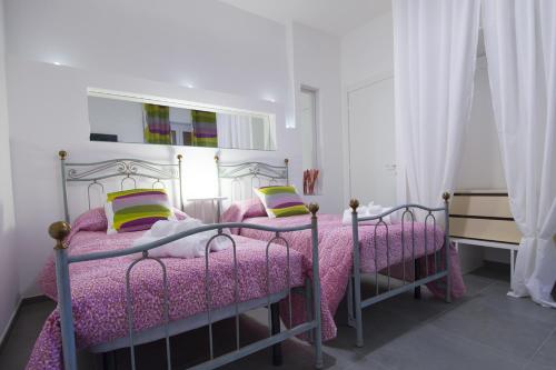 サン・ベネデット・デル・トロントにあるPianozero Roomのベッドルーム1室(ピンクのシーツと黄色の枕が備わるベッド2台付)