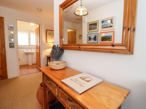 een badkamer met een houten tafel en een spiegel bij Yew Tree Cottage in Great Malvern