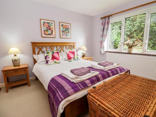 ein Schlafzimmer mit einem Bett mit violetter Bettwäsche und einem Fenster in der Unterkunft Yew Tree Cottage in Great Malvern