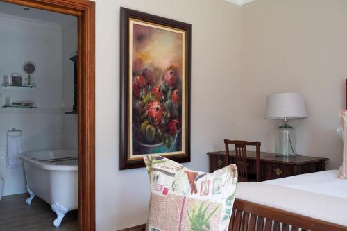 a bedroom with a painting on the wall and a bath tub at Issaquena Heights Boutique Hotel in Knysna