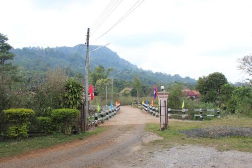 Un camino de tierra junto a una valla con banderas. en Theokhame Guest House & Hotel, en Ban Tayun