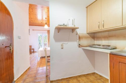 una cucina con pareti bianche e armadi in legno di Korina Studios a Paleokastritsa