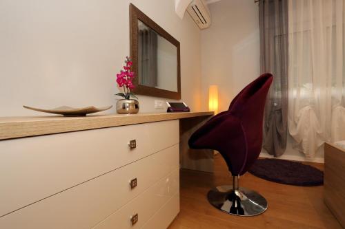 czerwone krzesło siedzące na komodzie w łazience w obiekcie Luxury Maraschino Apartments w mieście Zadar