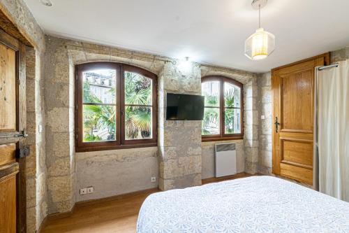 ein Schlafzimmer mit einem Bett und einigen Fenstern in der Unterkunft Superbe appartement, situé au cœur de la ville. in Auch