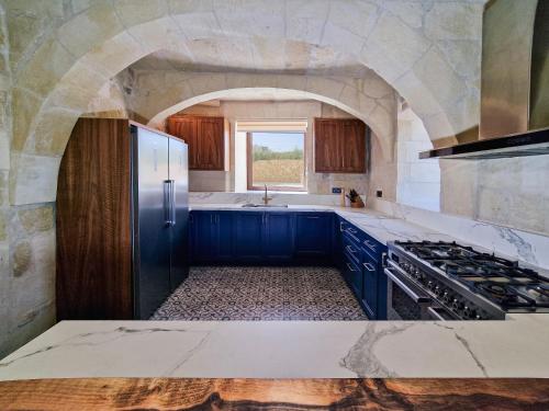 una cocina con armarios azules y una gran ventana en Luxury Farmhouse Villa surrounded with Nature & Farm Animals Alpacas etc, en Għasri