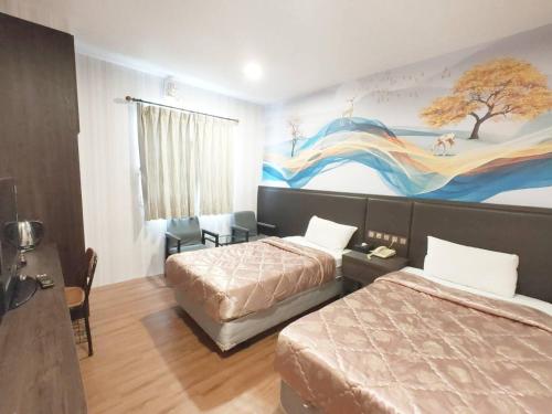 una habitación de hotel con 2 camas y un cuadro en la pared en Royal Business Hotel, en Nantou City