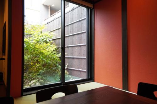 a room with a table and a large window at MUSUBI Sanjo Bettei in Kyoto