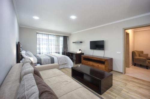 a living room with a couch and a television at Coresi rezidence & suites in Braşov