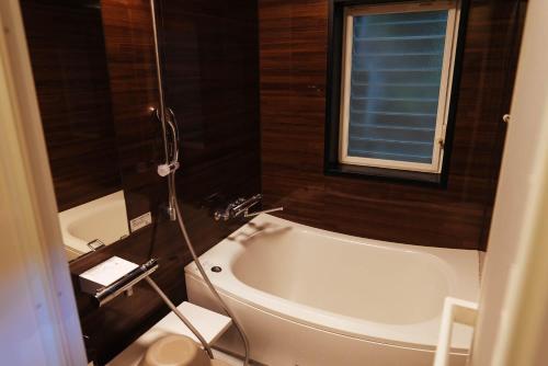 a bathroom with a bath tub and a window at Villa Yumigahama in Minamiizu