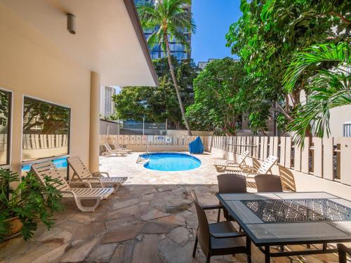 a patio with chairs and a swimming pool at Penthouse in Waikiki with ocean & mountain views in Honolulu