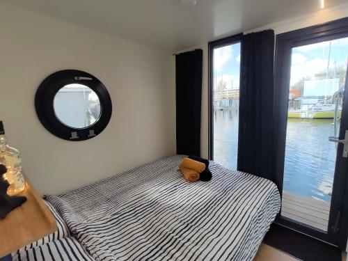 una cama con un osito de peluche sentado en ella junto a una ventana en Hausboot Hilja - neuer Ankerplatz!, en Schleswig