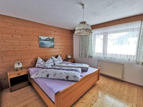 a bedroom with a large bed and a wooden wall at Haus Steinkarblick und Berghäusl in Berwang