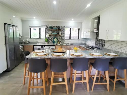 a kitchen with a large island with chairs around it at The Bird Hide Luxury Self catering in White River