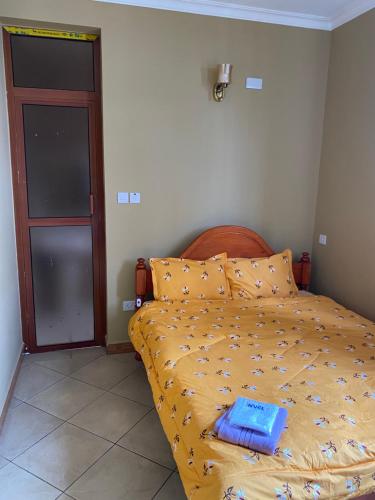 um quarto com uma cama com um edredão amarelo em Hein apartment em Arusha
