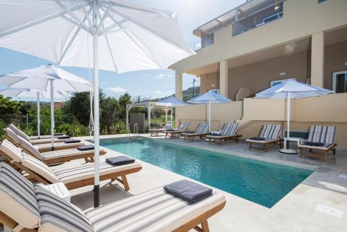 una piscina con sillas y sombrillas junto a una casa en Meliora Suites en Dhrapaniás