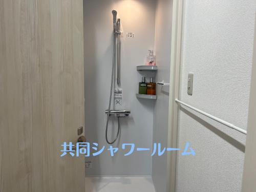 een douche in een badkamer naast een deur bij Hostel Mallika in Hiroshima