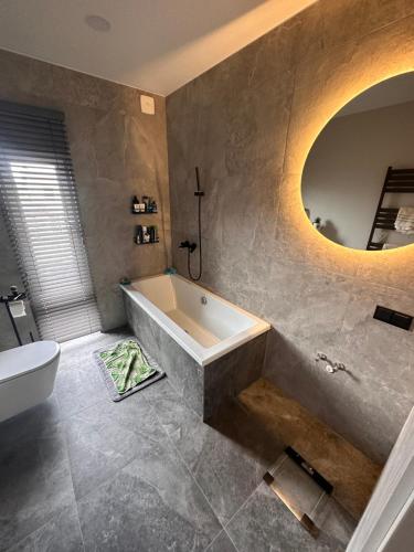 a bathroom with a tub and a toilet and a mirror at Apartment over two floors in Kaunas