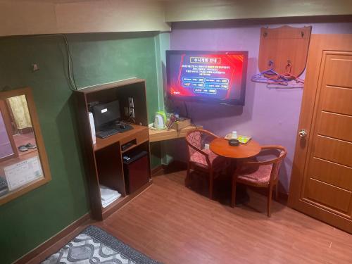 um quarto com uma secretária e uma mesa com uma televisão em Grace Motel em Seul