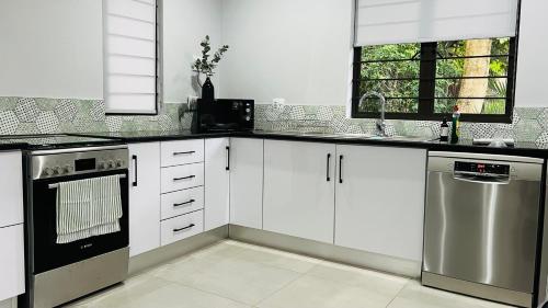 una cocina con armarios blancos y electrodomésticos de acero inoxidable en Robyns Nest 3 Self Catering Flat en Kloof