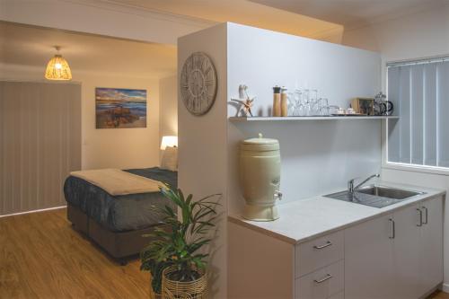 uma cozinha com um lavatório e uma cama num quarto em Coola studio em Mallacoota