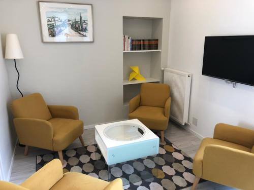 a waiting room with two chairs and a flat screen tv at La Maison de Jules in Paray-le-Monial