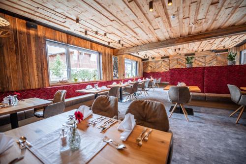 un restaurante con paredes de madera, mesas y sillas en Hotel Lohningerhof, en Maria Alm am Steinernen Meer