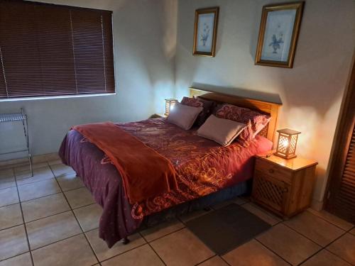 um quarto com uma cama com um edredão vermelho em Da Gama Lake Cottages - Coral Tree and Cormorant Cottages em White River