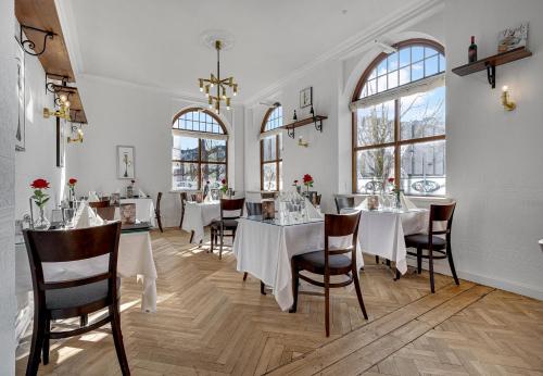 ein Esszimmer mit weißen Tischen, Stühlen und Fenstern in der Unterkunft Hotel Phønix Brønderslev in Brønderslev