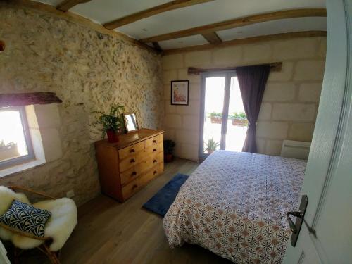 a bedroom with a bed and a dresser and a window at La Bienheureuse Maison, vue sur le Château de Villandry in Villandry