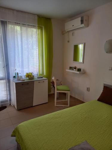 a bedroom with a green bed and a desk and window at Венета 1 in Sozopol