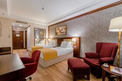 a hotel room with two beds and a chair at Wellborn Luxury Hotel in Kocaeli