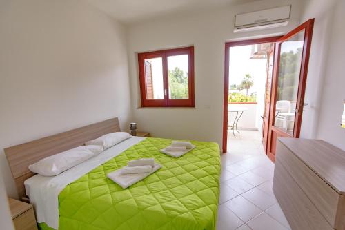 una camera da letto con un letto con una coperta verde sopra di SanvitoTour - Appartamenti Il Mulino a San Vito lo Capo