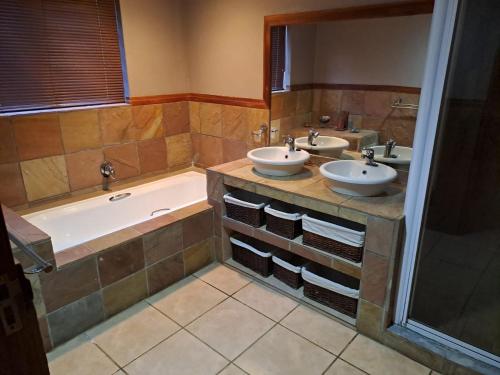 a bathroom with two sinks and a bath tub at Da Gama Lake Cottages - Coral Tree and Cormorant Cottages in White River
