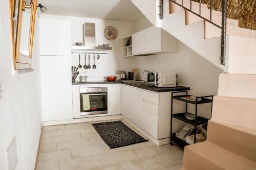 een kleine keuken met witte kasten en een trap bij Sa Rocca in Bosa