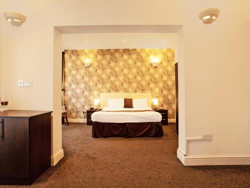 a bedroom with a bed and two tables and a wall at The Waverley Hotel in Great Yarmouth