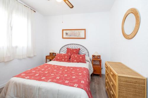 a bedroom with a bed with red pillows and a mirror at Cortijo Ginatar in Dúrcal