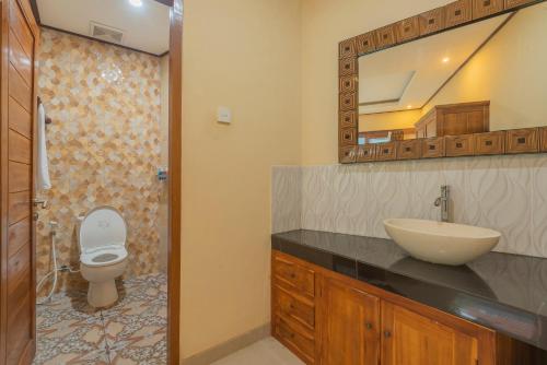 La salle de bains est pourvue d'un lavabo, de toilettes et d'un miroir. dans l'établissement Liliy Guest House Kuta - Badung, à Legian