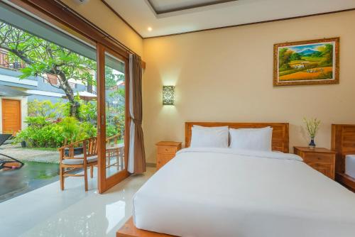 Liliy Guest House Kuta - Badung في ليغِيان: غرفة نوم بسرير ونافذة كبيرة