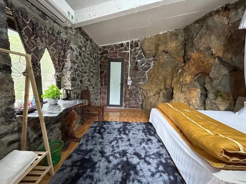 a bedroom with a stone wall at Yen Nhi Homestay Ban Gioc in Cao Bằng