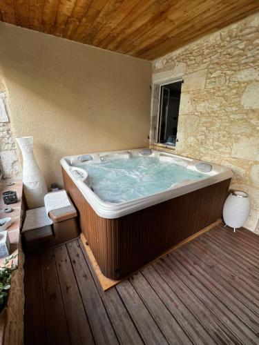 uma grande banheira sentada num deque de madeira em Chambre d hôte petit crussac em Mauvezin